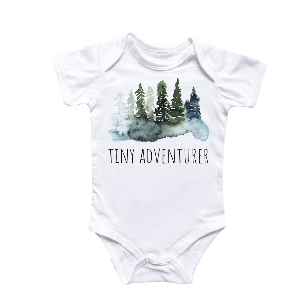 a white bodysuit with trees and the words tiny adventurer on it