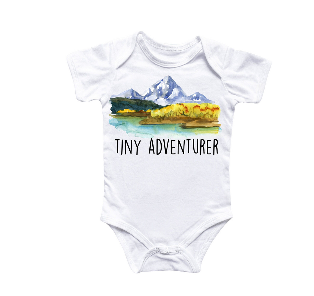 a white bodysuit with a picture of a mountain and the words tiny adventurer on