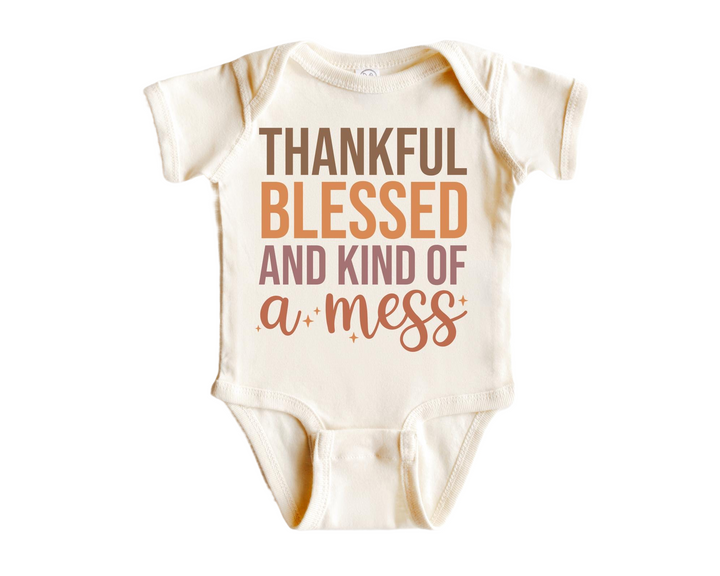 a baby bodysuit that says, thank, and kind of a mess