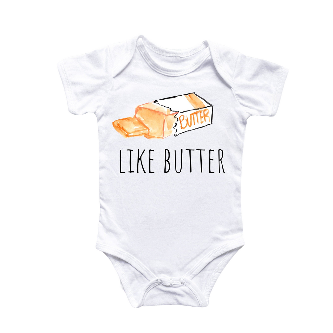 a white baby bodysuit with an orange slice of butter on it