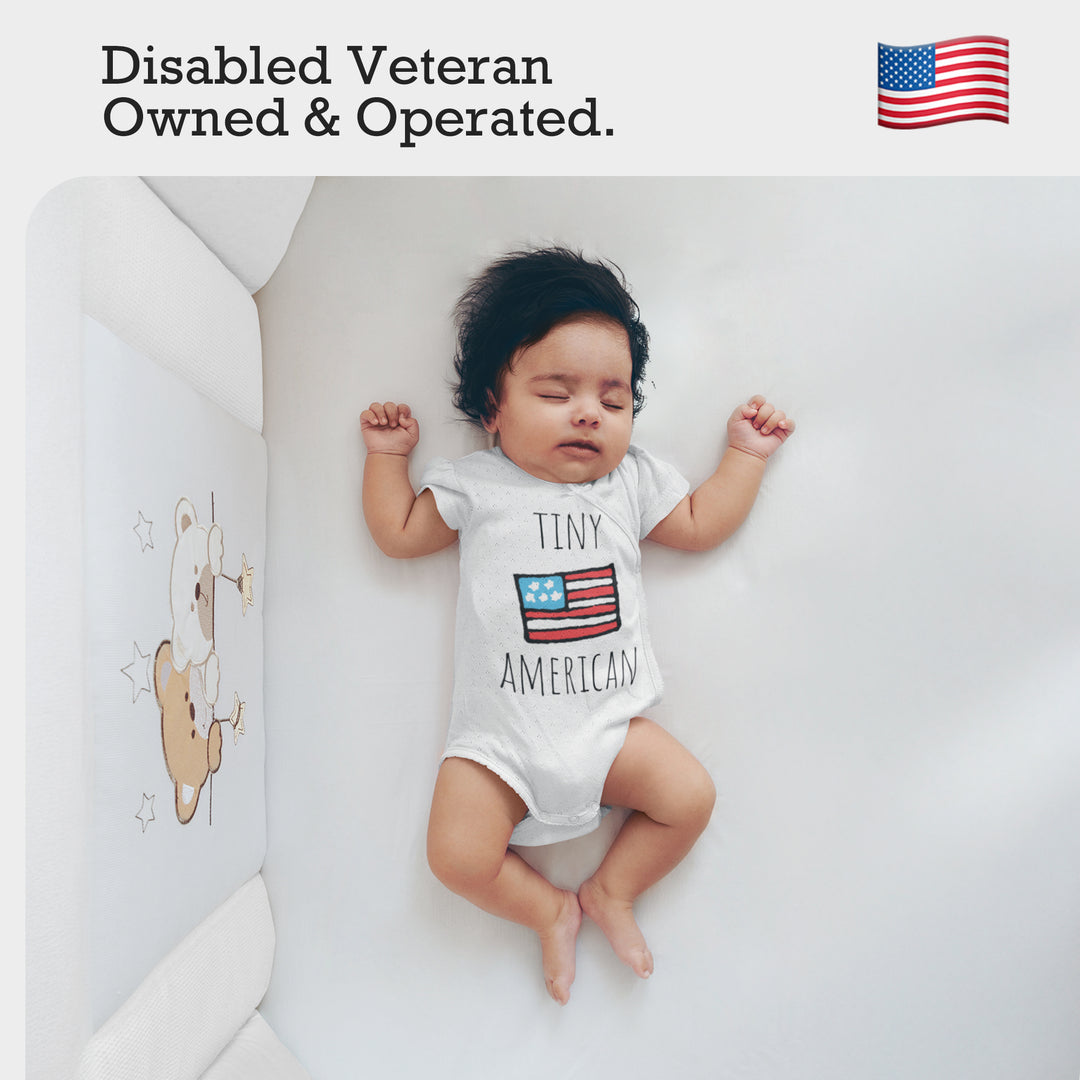 a baby laying on a bed with an american flag on it