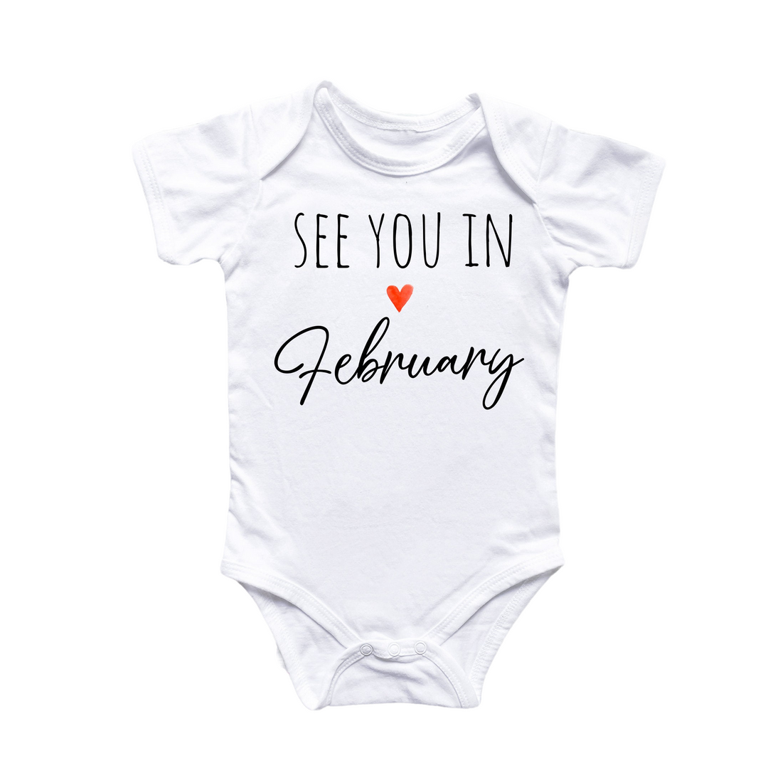 a white baby bodysuit with the words see you in february