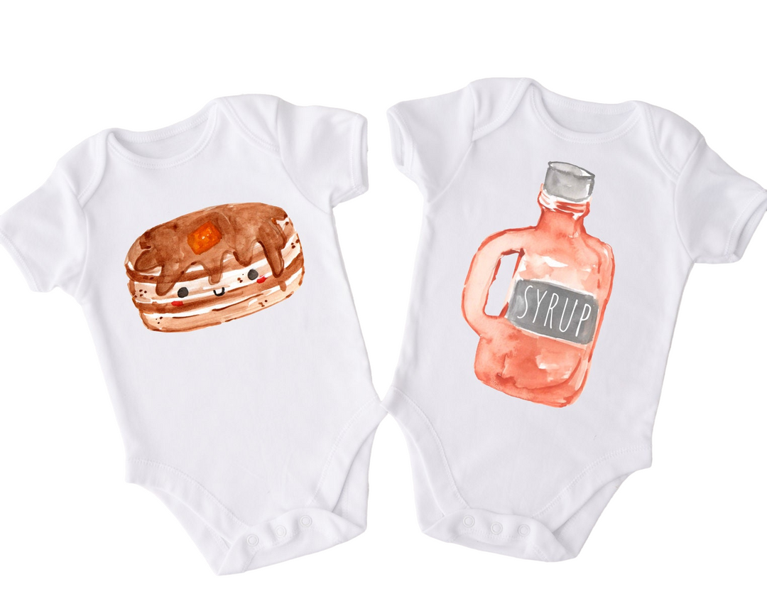 two baby onesuits with a bottle of syrup and a sandwich