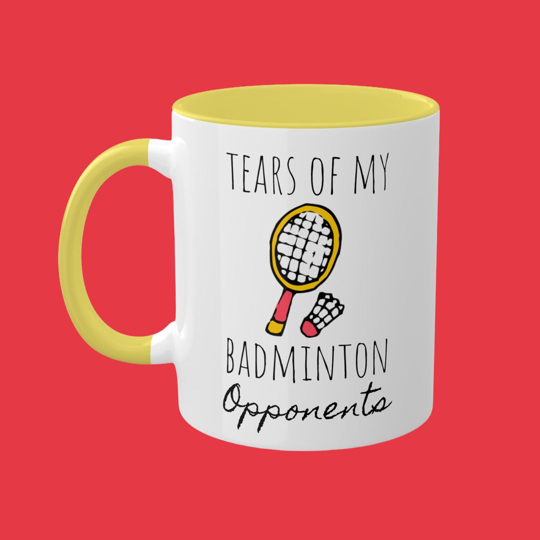a yellow and white coffee mug with the words tears of my badminton opponent