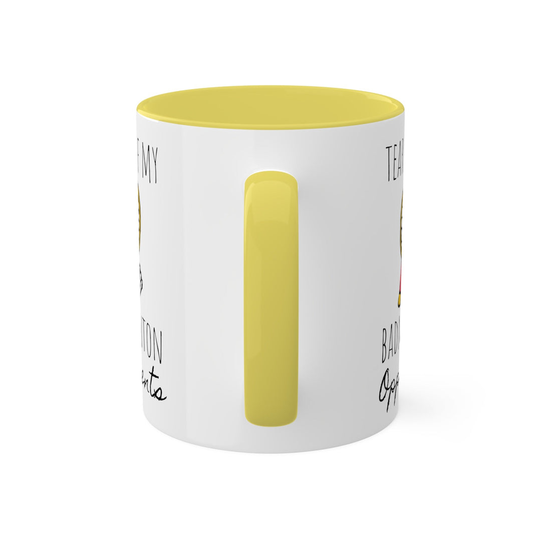 a white and yellow coffee mug with a yellow handle