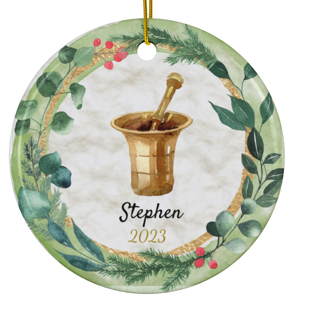 a christmas ornament with a gold mortar and holly wreath